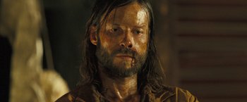 Movie still from “The Proposition” (2005), directed by John Hillcoat – A person with long hair and a beard; Close Up shot, High angle