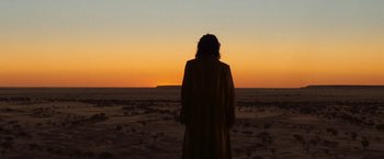 Movie still from “The Proposition” (2005), directed by John Hillcoat – A person standing in the middle of an open field; Extreme Wide shot, Over the shoulder angle