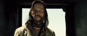 Movie still from “The Proposition” (2005), directed by John Hillcoat – A man with long black hair and a beard; Close Up shot, Over the shoulder angle