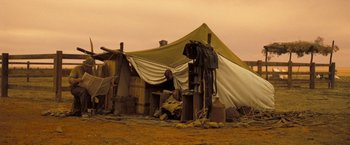 Movie still from “The Proposition” (2005), directed by John Hillcoat – A tent with a man sitting in front of it; Wide shot, Low angle