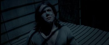 Movie still from “The Proposition” (2005), directed by John Hillcoat – A man with long black hair and a bandage on his face; Close Up shot, High angle