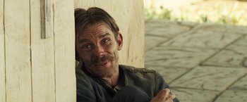 Movie still from “The Proposition” (2005), directed by John Hillcoat – A man sitting on the side of a wall; Close Up shot, High angle