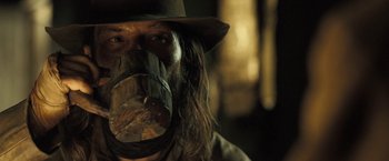 Movie still from “The Proposition” (2005), directed by John Hillcoat – A man wearing a hat and a mask with long brown hair; Close Up shot, Low angle