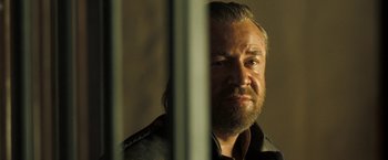 Movie still from “The Proposition” (2005), directed by John Hillcoat – A person behind a metal fence; Close Up shot, Over the shoulder angle