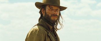 Movie still from “The Proposition” (2005), directed by John Hillcoat – A man with long hair wearing a hat and beard; Close Up shot, Low angle