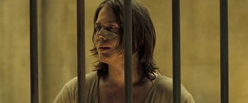 Movie still from “The Proposition” (2005), directed by John Hillcoat – A man with bandages on his face is behind bars; Close Up shot, Low angle