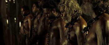 Movie still from “The Proposition” (2005), directed by John Hillcoat – A group of men standing next to each other with chains around their necks; Medium shot, High angle