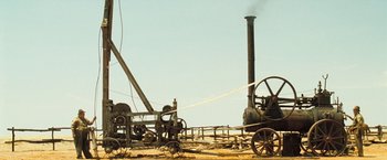 Movie still from “The Proposition” (2005), directed by John Hillcoat – An old steam engine sitting on top of a dirt field; Extreme Wide shot, Low angle