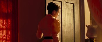 Movie still from “The Proposition” (2005), directed by John Hillcoat – A woman standing in front of an open door; Medium shot, Over the shoulder angle