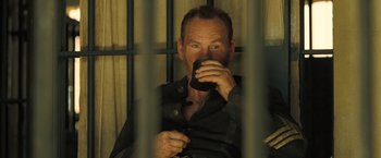 Movie still from “The Proposition” (2005), directed by John Hillcoat – A man sitting in a jail cell drinking coffee; Close Up shot, High angle
