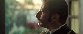 Movie still from “The Proposition” (2005), directed by John Hillcoat – A person wearing a suit and tie; Close Up shot, Over the shoulder angle