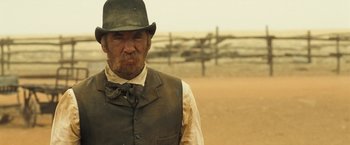 Movie still from “The Proposition” (2005), directed by John Hillcoat – An old man in a hat and vest standing in a field; Close Up shot, Over the shoulder angle