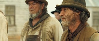 Movie still from “The Proposition” (2005), directed by John Hillcoat – Two old men wearing hats are standing next to each other; Close Up shot, Low angle