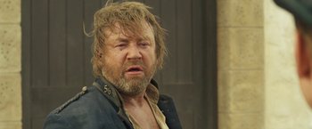 Movie still from “The Proposition” (2005), directed by John Hillcoat – A man with a beard and a jacket on; Close Up shot, Low angle