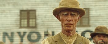 Movie still from “The Proposition” (2005), directed by John Hillcoat – An older man wearing a hat and a vest; Close Up shot, Low angle