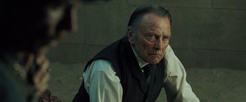 Movie still from “The Proposition” (2005), directed by John Hillcoat – An older man in a black vest and a white shirt; Close Up shot, Over the shoulder angle