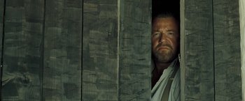 Movie still from “The Proposition” (2005), directed by John Hillcoat – A man standing next to a wooden wall; Close Up shot, Low angle