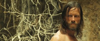 Movie still from “The Proposition” (2005), directed by John Hillcoat – A man with long hair and a bare chest; Close Up shot, Low angle