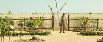 Movie still from “The Proposition” (2005), directed by John Hillcoat – A man standing in front of a wooden fence; Wide shot, Over the shoulder angle
