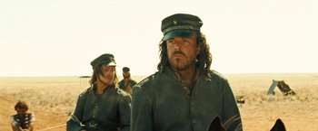 Movie still from “The Proposition” (2005), directed by John Hillcoat – A man in a military uniform with long hair and a hat; Medium shot, Low angle