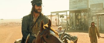 Movie still from “The Proposition” (2005), directed by John Hillcoat – A man riding a horse in the middle of the desert; Medium shot, Over the shoulder angle
