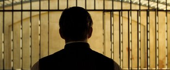 Movie still from “The Proposition” (2005), directed by John Hillcoat – A man standing in front of a jail cell; Medium shot, Over the shoulder angle
