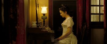 Movie still from “The Proposition” (2005), directed by John Hillcoat – A woman in a white dress standing in front of a mirror; Medium shot, High angle