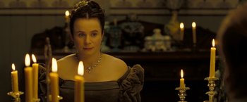 Movie still from “The Proposition” (2005), directed by John Hillcoat – A woman in a black dress is looking at a lit candle; Close Up shot, Over the shoulder angle