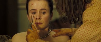 Movie still from “The Proposition” (2005), directed by John Hillcoat – A woman with scissors in her hand and a knife in her other hand; Close Up shot, Over the shoulder angle