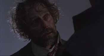 Movie still from “The Punisher” (1989), directed by Mark Goldblatt – A person wearing a suit and tie; Close Up shot, Over the shoulder angle