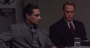 Movie still from “The Punisher” (1989), directed by Mark Goldblatt – A man in a suit sitting next to another man in a suit; Close Up shot, Over the shoulder angle