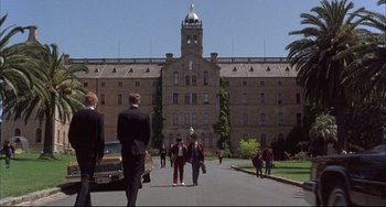 Movie still from “The Punisher” (1989), directed by Mark Goldblatt – A group of people walking down a street near a building; Extreme Wide shot, High angle