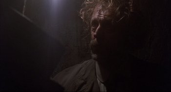 Movie still from “The Punisher” (1989), directed by Mark Goldblatt – A person with curly hair and a beard; Close Up shot, Over the shoulder angle