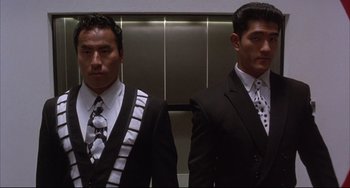 Movie still from “The Punisher” (1989), directed by Mark Goldblatt – A couple of men standing next to each other in suits; Medium shot, Low angle