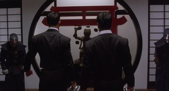 Movie still from “The Punisher” (1989), directed by Mark Goldblatt – A couple of men standing next to each other in a room; Medium shot, Low angle