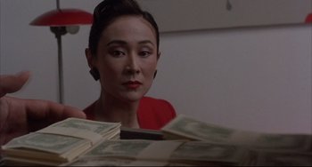 Movie still from “The Punisher” (1989), directed by Mark Goldblatt – A woman sitting in front of a pile of money; Close Up shot, Low angle