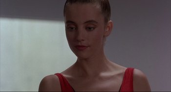 Movie still from “The Punisher” (1989), directed by Mark Goldblatt – A young woman in a red top is looking at the camera; Close Up shot, Over the shoulder angle