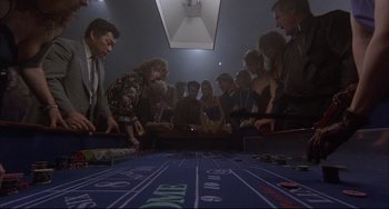 Movie still from “The Punisher” (1989), directed by Mark Goldblatt – A group of people standing around a game table; Wide shot, High angle