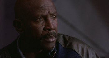 Movie still from “The Punisher” (1989), directed by Mark Goldblatt – An older black man with a mustache looking at the camera; Close Up shot, Low angle