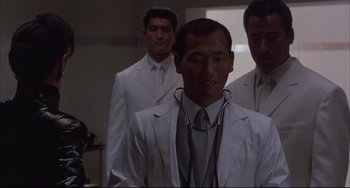 Movie still from “The Punisher” (1989), directed by Mark Goldblatt – A group of men standing next to each other in a room; Medium shot, Low angle