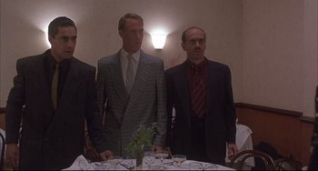 Movie still from “The Punisher” (1989), directed by Mark Goldblatt – A group of men standing in front of a dinner table; Medium shot, Low angle