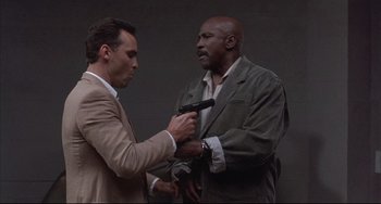 Movie still from “The Punisher” (1989), directed by Mark Goldblatt – A man holding a gun and another man holding a gun; Medium shot, Low angle