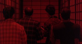 Movie still from “The Punisher” (1989), directed by Mark Goldblatt – A group of people standing next to each other in a room; Medium shot, Over the shoulder angle