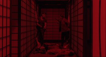 Movie still from “The Punisher” (1989), directed by Mark Goldblatt – Two men are standing in an empty room with guns; Wide shot, High angle