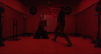 Movie still from “The Punisher” (1989), directed by Mark Goldblatt – Two people practicing martial arts in a red room; Wide shot, Low angle