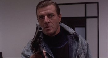 Movie still from “The Punisher” (1989), directed by Mark Goldblatt – A man holding a gun in his hand; Close Up shot, Low angle