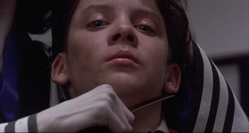 Movie still from “The Punisher” (1989), directed by Mark Goldblatt – A young boy is holding a pair of scissors in his hand; Close Up shot, Low angle