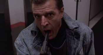 Movie still from “The Punisher” (1989), directed by Mark Goldblatt – A person holding a gun in his mouth; Close Up shot, Low angle