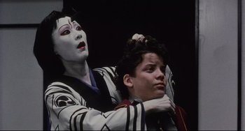 Movie still from “The Punisher” (1989), directed by Mark Goldblatt – A man sitting next to a woman with a mask on; Close Up shot, Low angle