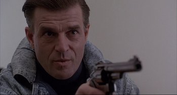 Movie still from “The Punisher” (1989), directed by Mark Goldblatt – A person holding a gun; Close Up shot, Low angle